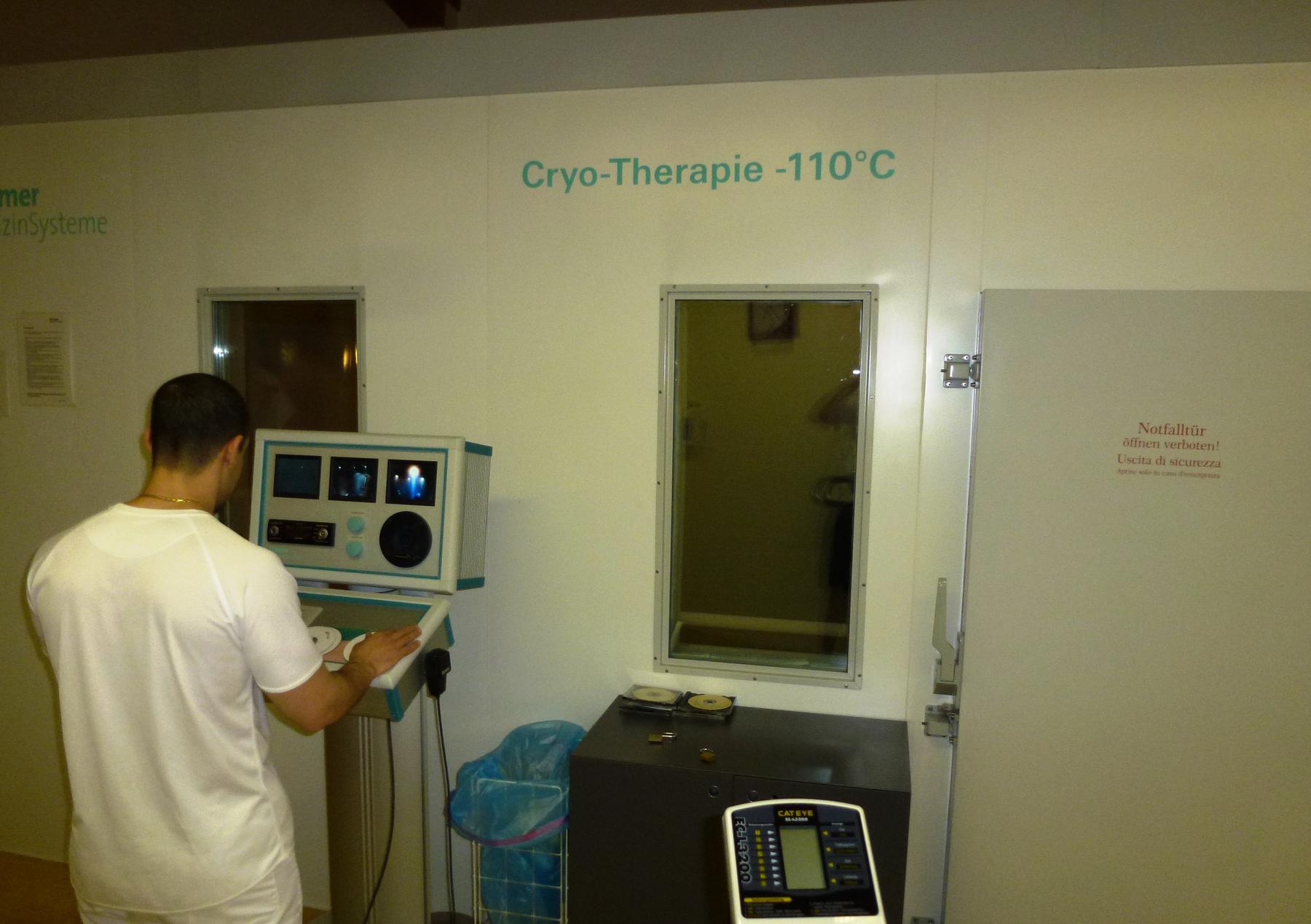 a man in a white shirt is standing in front of a computer - File:Cryo-Therapy Chamber Operation.JPG